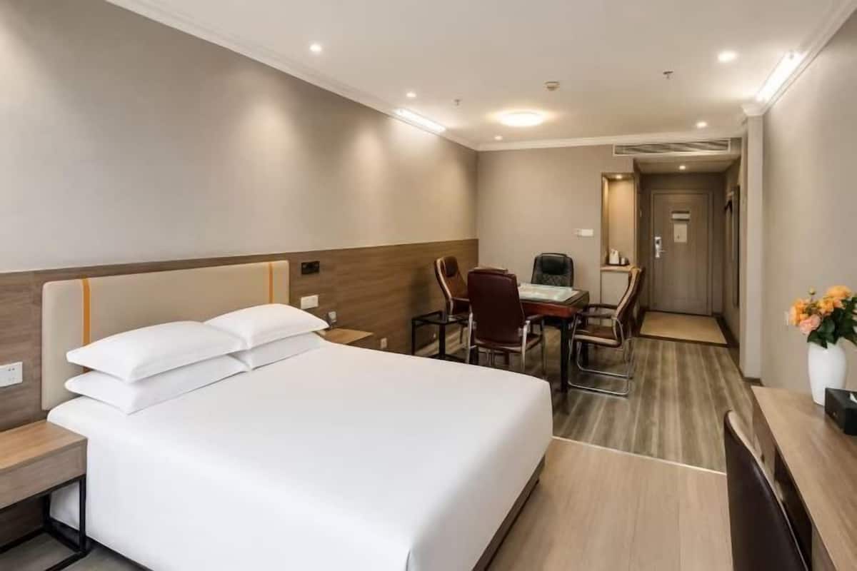 Ein Hotelzimmer mit Bett, Schreibtisch, Stühlen und einem kleinen Tisch.