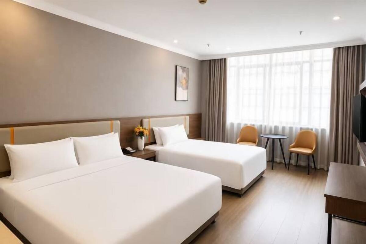 Ein Hotelzimmer mit zwei Betten, einem kleinen Tisch, einem Stuhl und einem Fernseher.