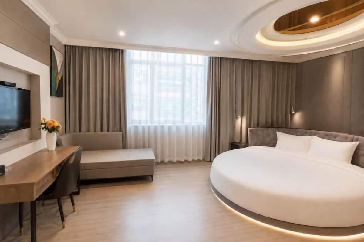 Ein modernes Hotelzimmer mit einem großen Bett, einem Schreibtisch, einer Couch und einem Fernseher.