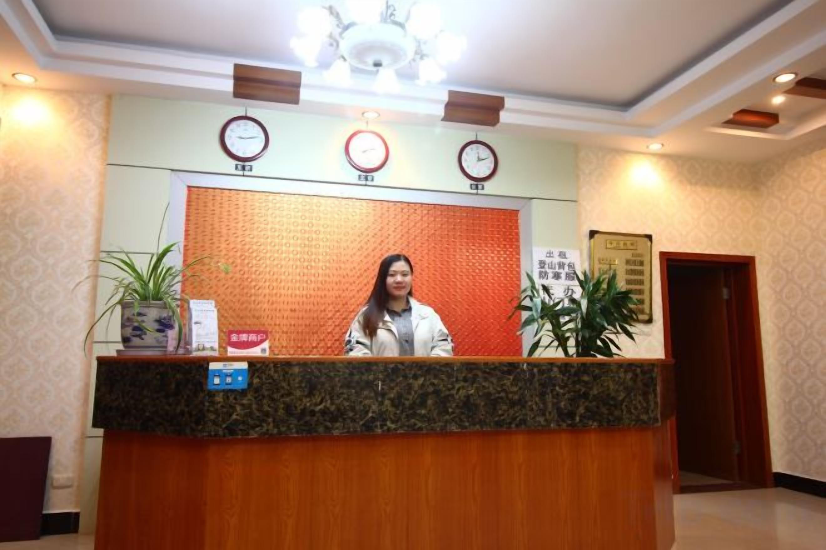 A reception desk with a clock, a sign, and a potted plant.