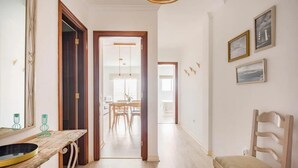 A hallway with a wooden table, a chair, and a door leading to another room. - Casa Paradise Sunset El Cotillo (El Cotillo)
