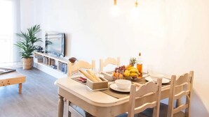 A dining area with a table set for two, featuring a bread basket, fruits, a bottle, and a bowl. - Casa Paradise Sunset El Cotillo (El Cotillo)