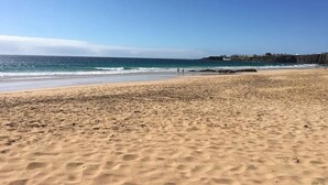 A beach with a clear sky, sandy shore, and a distant rocky coastline. - Casa Paradise Sunset El Cotillo (El Cotillo)