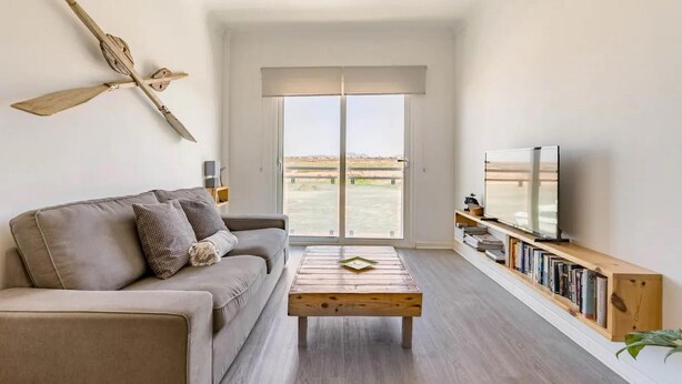 A modern living room with a sofa, coffee table, and a bookshelf with books. - Casa Paradise Sunset El Cotillo (El Cotillo)