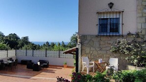 Une terrasse avec des meubles d’extérieur, un mur en pierre et une vue sur la mer.