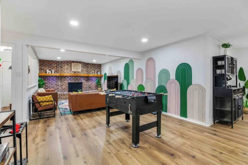 A room with a foosball table, a brick wall, and a sofa.