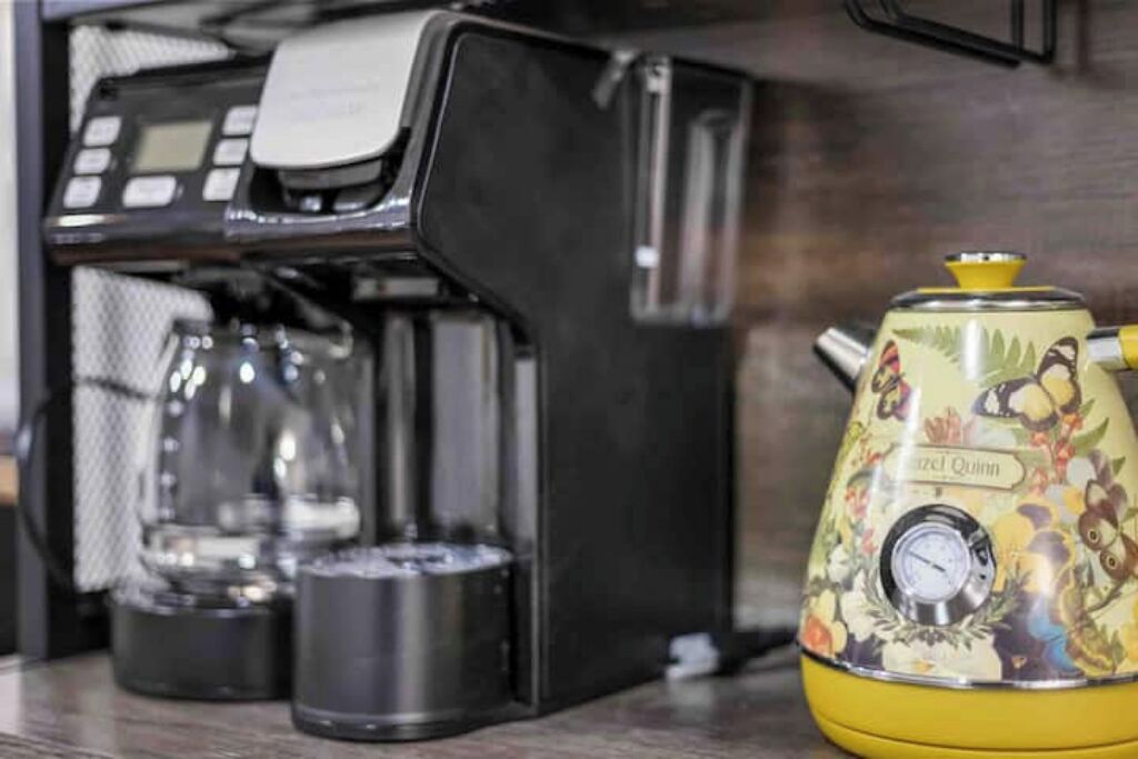 Een koffieapparaat en een waterkoker in retrostijl op een keukentafel.