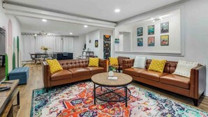 A living room with two brown leather sofas, a colorful rug, and a round coffee table. - The Whimsy Retreat-amazing pool-5Brs-houston prime location Beltway 8 & US 69 (Houston)