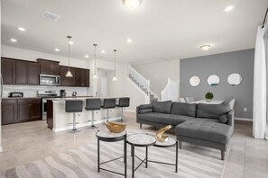 Relax in this stylish living space with a kitchen area, comfortable seating, and a staircase leading to an upper level.