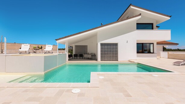 A modern two-story house with a swimming pool, outdoor seating, and a patio area.