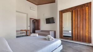 A bedroom with a bed, a desk, a chair, a television, and a sliding door.