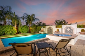 Ein Pool mit Whirlpool, umgeben von Palmen und Blick auf den Sonnenuntergang.