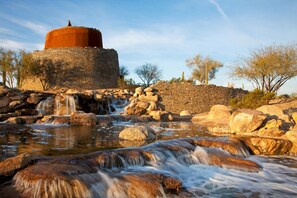 A stone structure with a water feature in front. - Charming Home in the Desert (Goodyear)