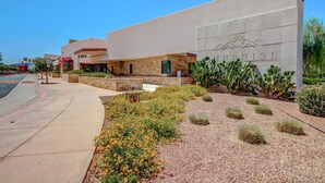 Un bâtiment sur lequel est apposée une grande enseigne portant le nom « PRISME », ainsi qu’un espace paysager agrémenté de diverses plantes et d’un sentier.