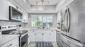 A modern kitchen with white cabinetry, a stainless steel refrigerator, a built-in oven, and a microwave. - Palm Tree Paradise Heated spa Pool Firepit (Glendale)