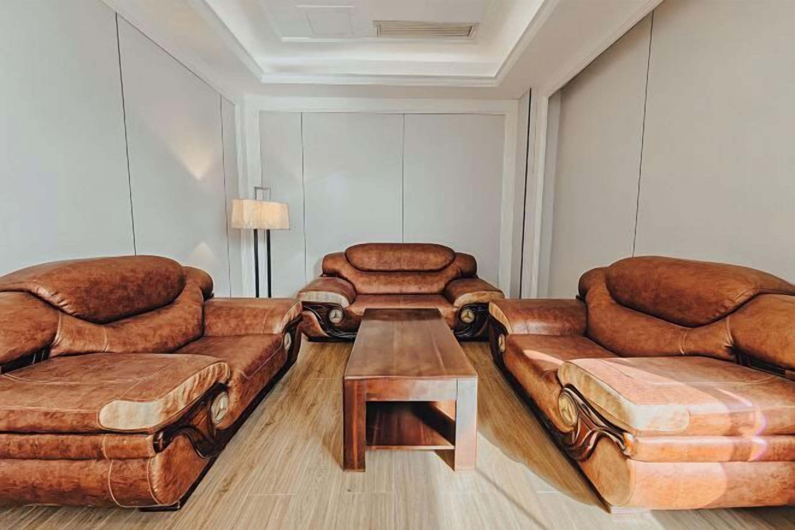 A room with two leather sofas facing each other, a wooden coffee table in the center, and a floor lamp on the left.