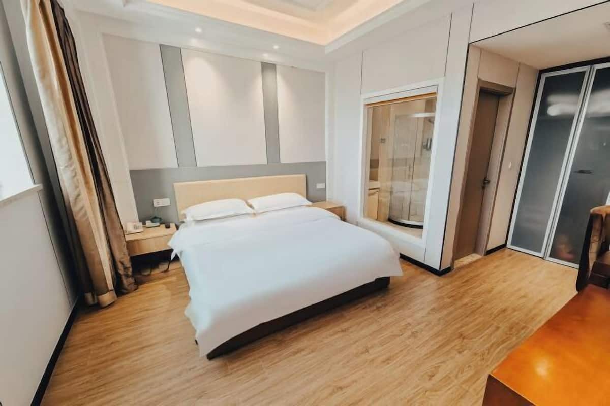Ein modernes Hotelzimmer mit einem großen Bett, einem Nachttisch, einem Schreibtisch und einem begehbaren Kleiderschrank.