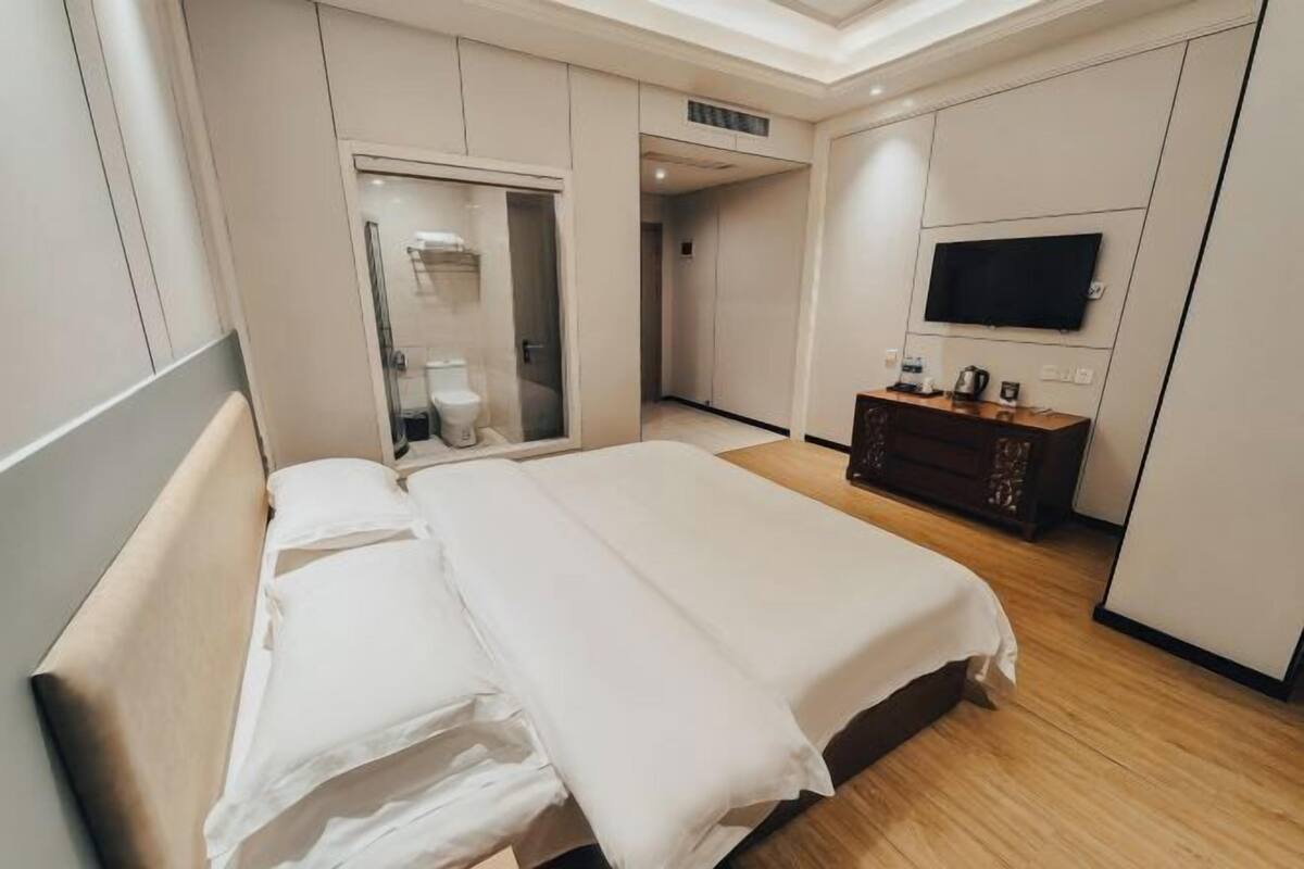 Ein Hotelzimmer mit Bett, Fernseher, Kleiderschrank und Badezimmer.