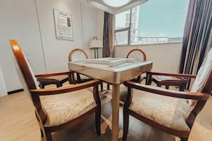Un comedor con una mesa y cuatro sillas, una ventana con cortinas y una lámpara fijada a la pared.