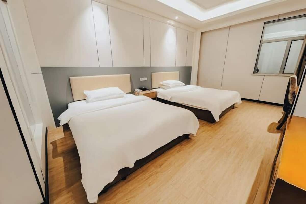 Ein Hotelzimmer mit zwei Betten, Holzboden und einem Oberlicht.