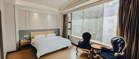 A hotel room with a large bed, a nightstand, a chair, and a small table.