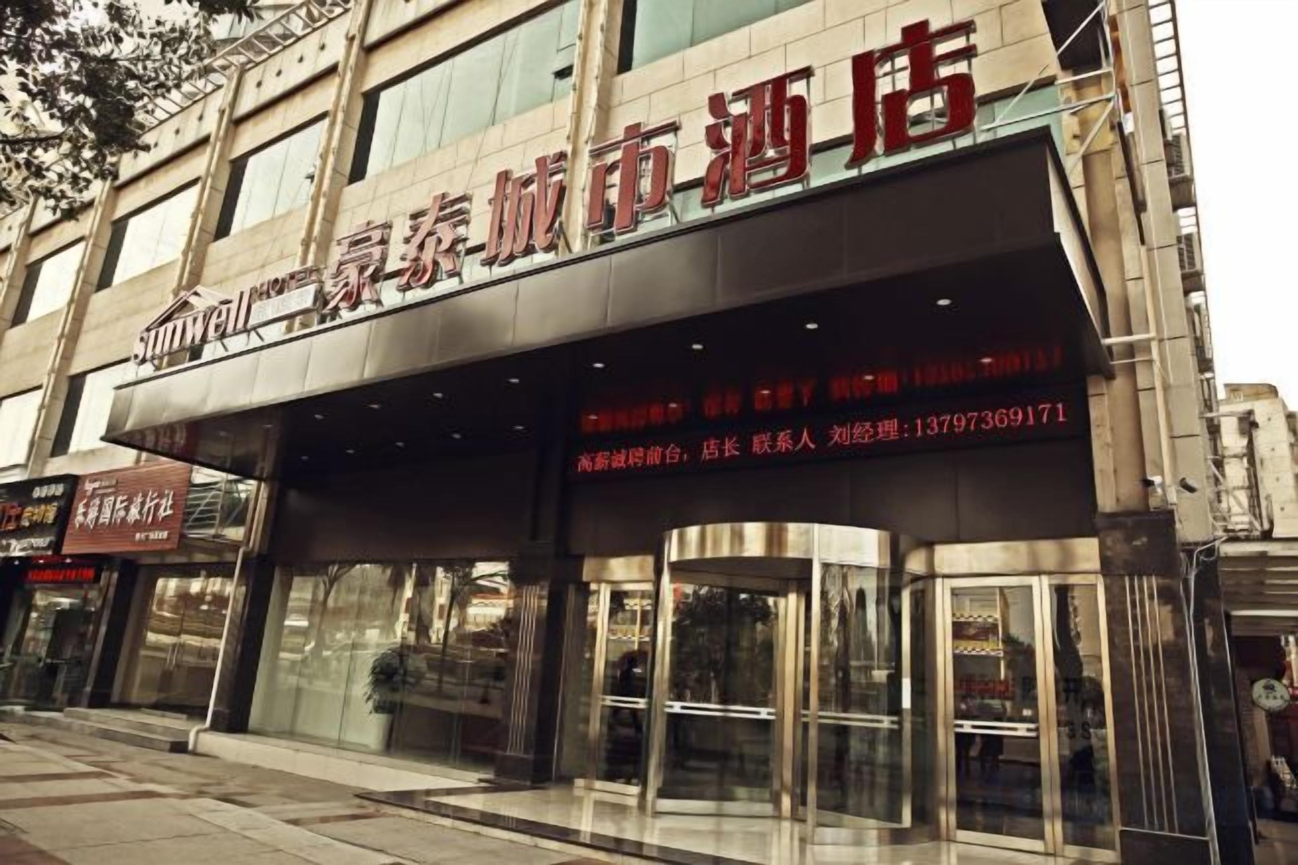 A hotel entrance with a glass door and a signboard above.