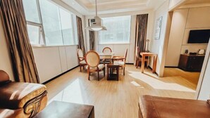 Ein modernes Hotelzimmer mit einem Holztisch, Stühlen, einer Couch und einem Fernseher.