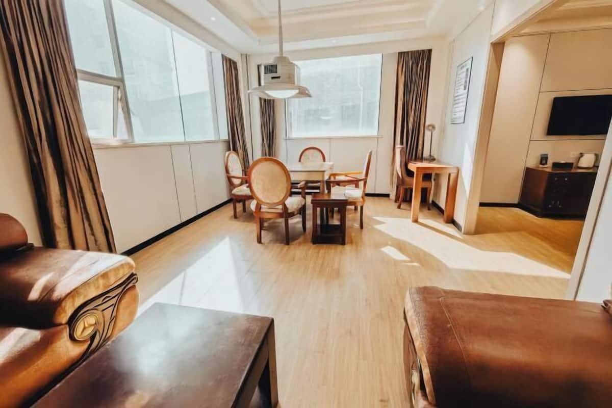 Ein modernes Hotelzimmer mit einem Holztisch, Stühlen, einer Couch und einem Fernseher.
