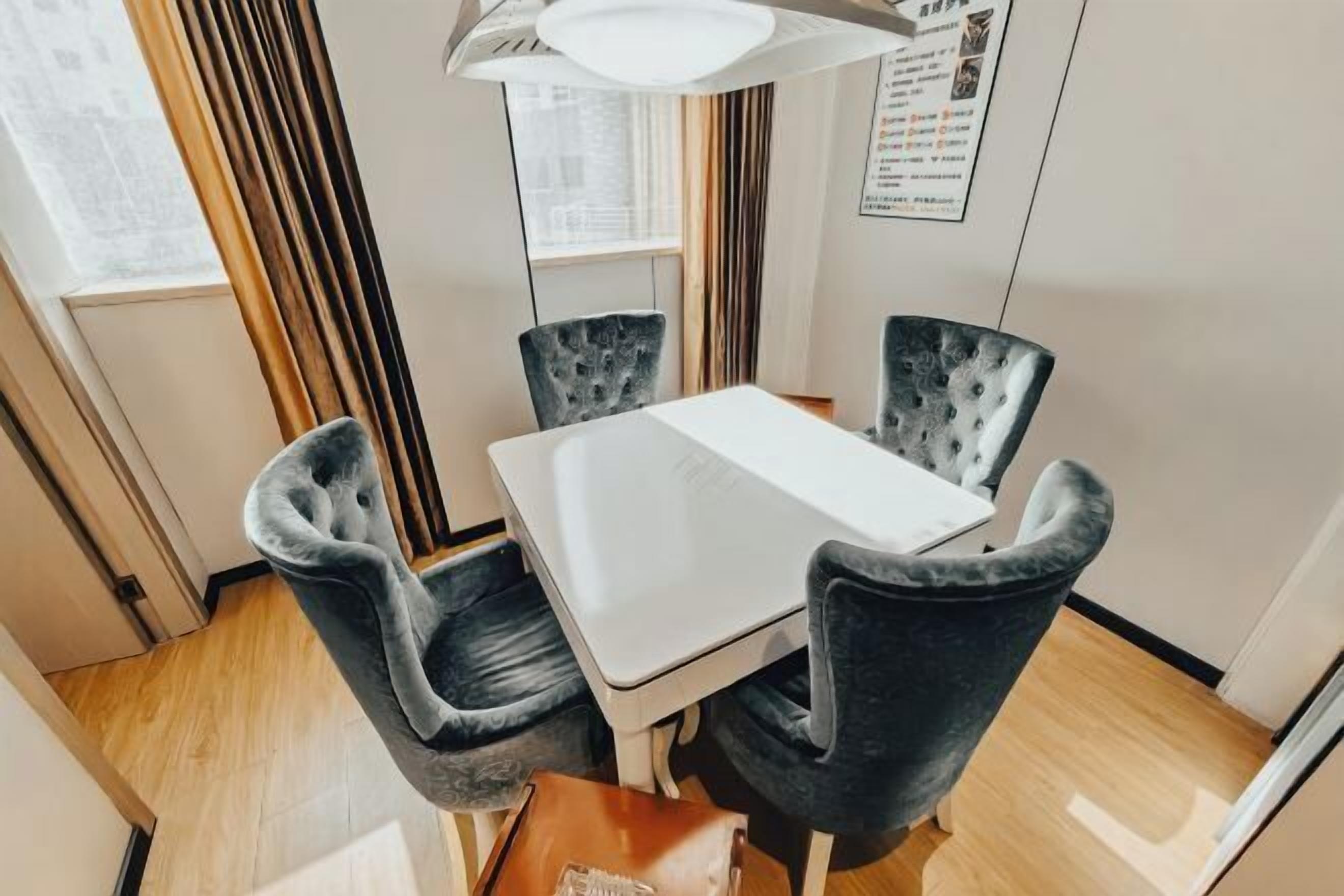 A dining area with a table and four chairs, a window with curtains, and a city view.