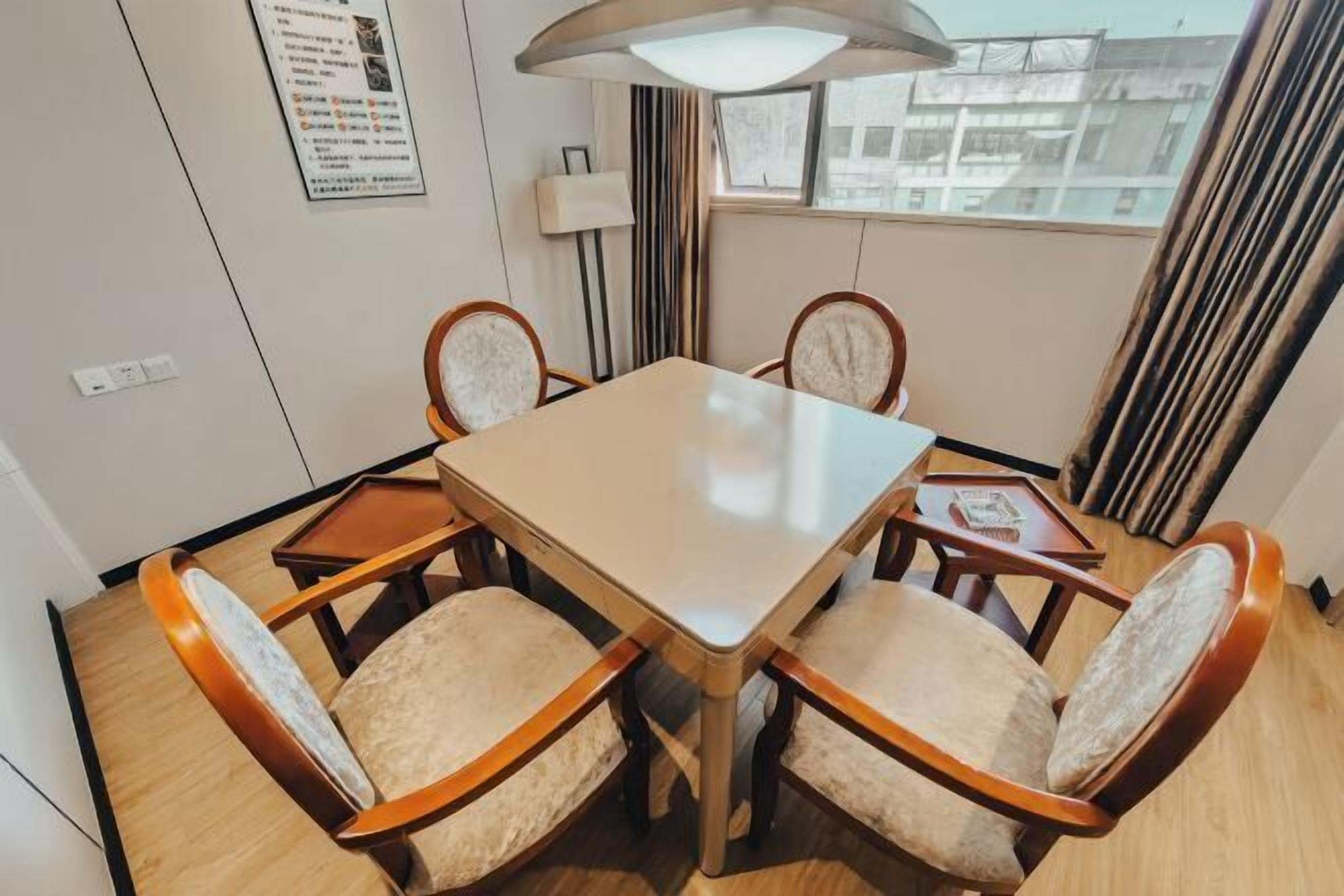 Un comedor con una mesa rectangular rodeada de cuatro sillas con asientos acolchados y reposabrazos de madera.