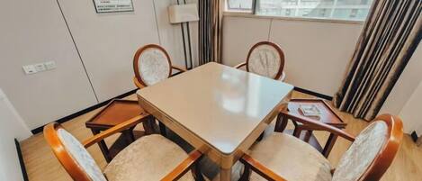 Un comedor con una mesa rectangular rodeada de cuatro sillas con asientos acolchados y reposabrazos de madera.