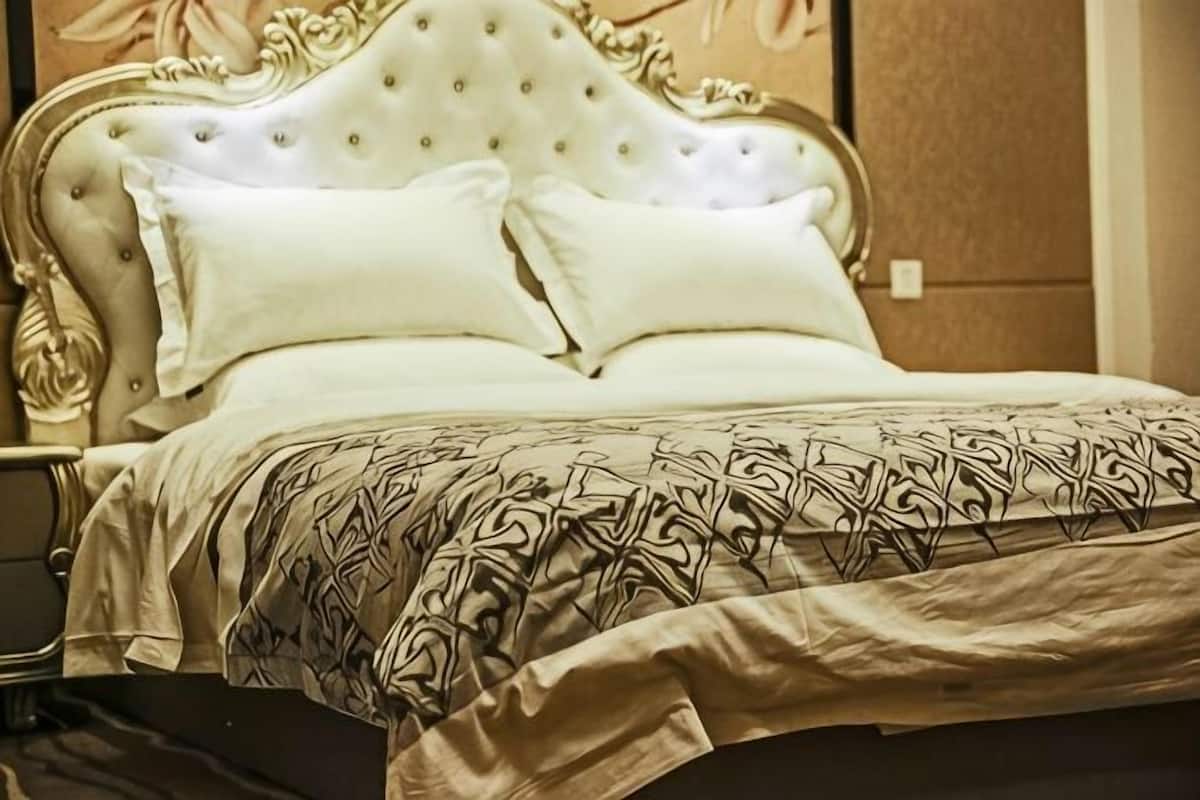 Ein Bett mit einer gebügelten Kopfteil, zwei Kissen und einer gemusterten Bettdecke.