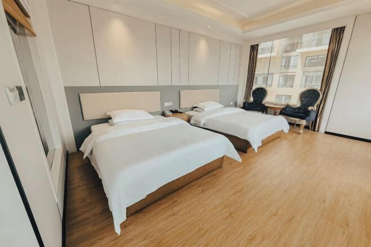 Une chambre d’hôtel avec deux lits, un bureau et une chaise.