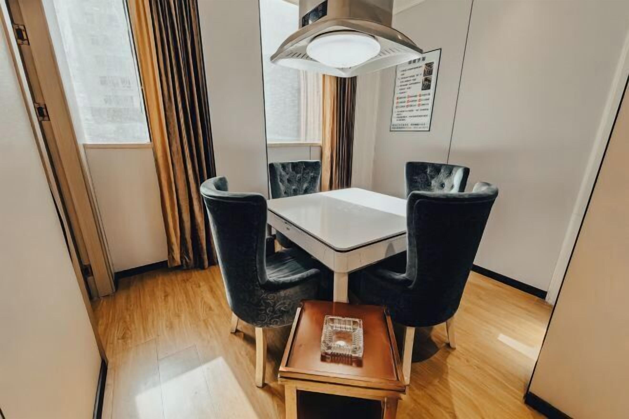 Un petit coin repas comprenant une table et quatre chaises, une petite table d’appoint et un luminaire suspendu au plafond.