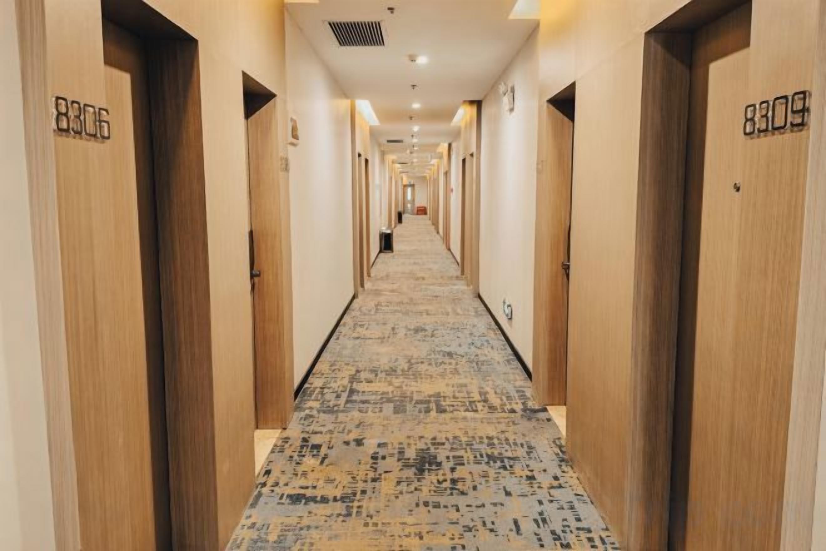 Un pasillo de hotel con puertas de madera, con los números 8306 y 8309, que dan a las habitaciones.