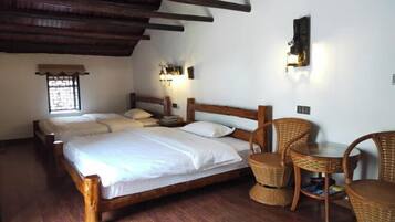 Una habitación con dos camas de madera, sillas de mimbre y una pequeña mesa.
