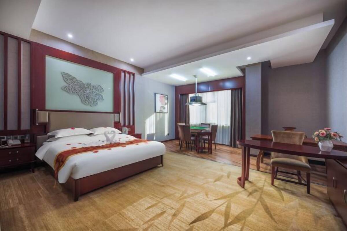 Une chambre d’hôtel avec un grand lit, un bureau et un coin repas.