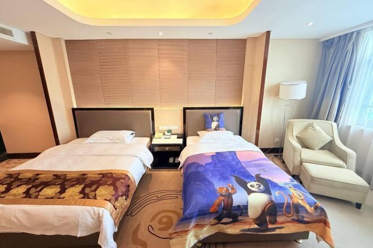 Une chambre d’hôtel avec deux lits, un canapé, une lampe et une fenêtre avec des rideaux.
