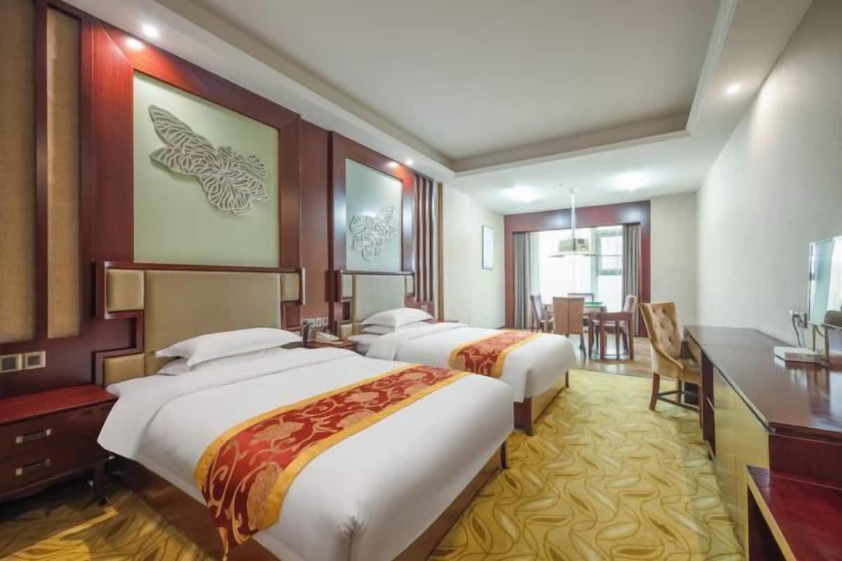 Une chambre d’hôtel avec deux lits, un bureau, une chaise et un coin repas.