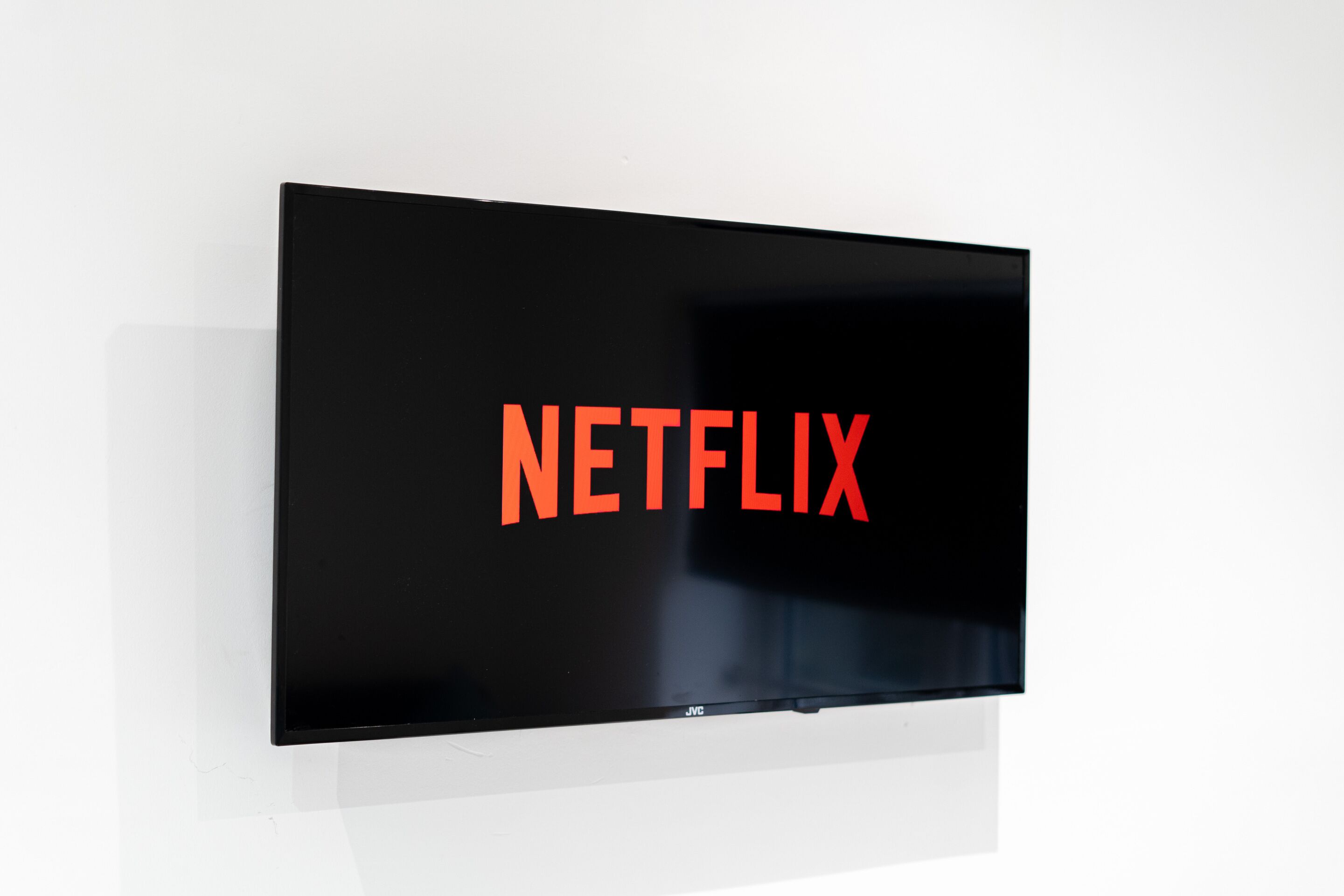Een flatscreen televisie bevestigd aan een muur, waarop het Netflix-logo wordt getoond.