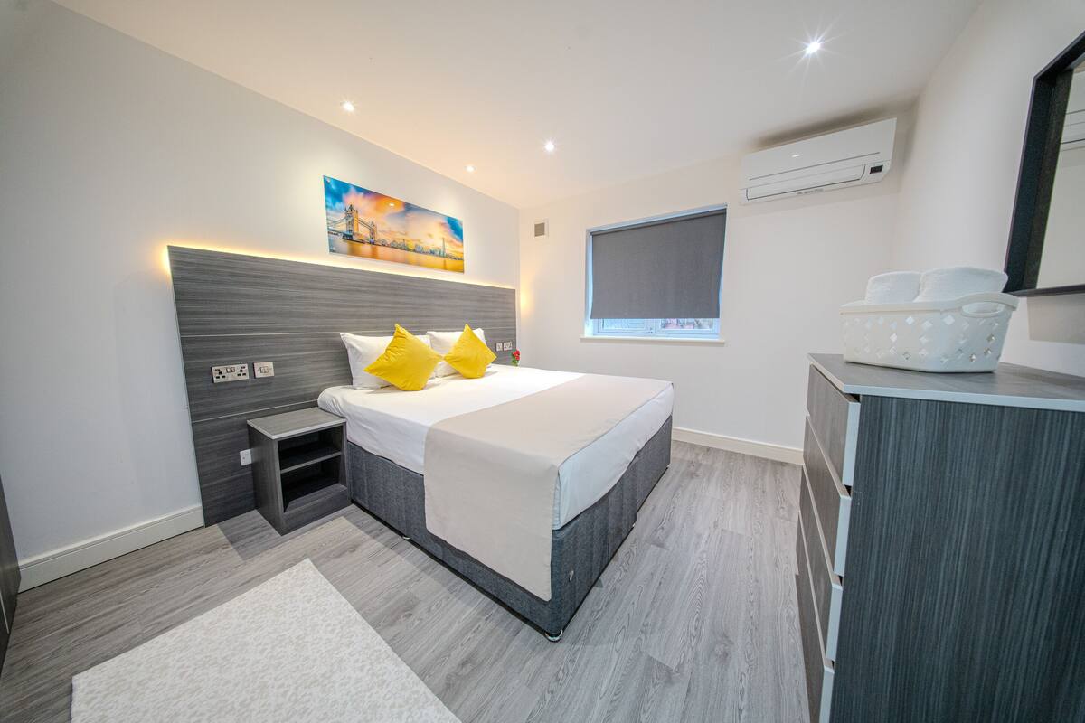 Een moderne slaapkamer met een bed, nachtkastjes, een kaptafel en een schilderij aan de muur.