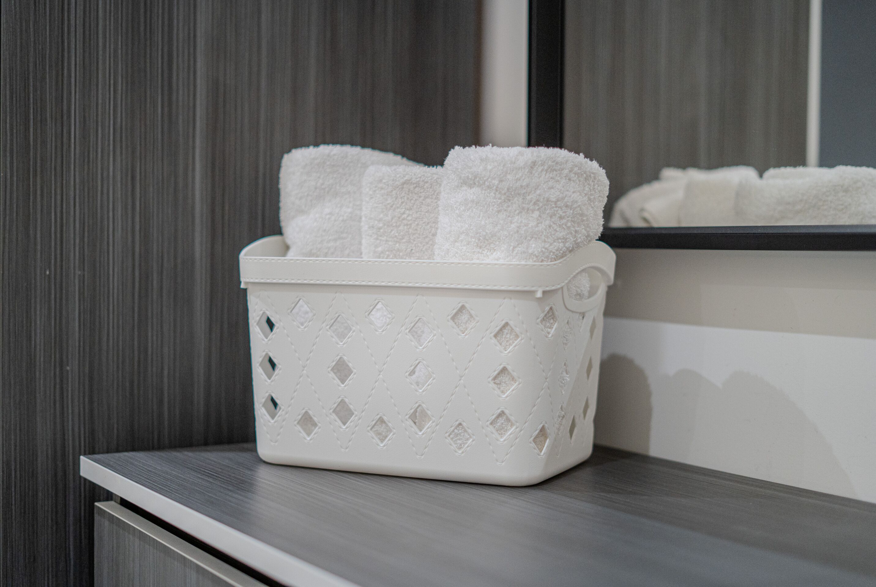 A white laundry basket with a diamond pattern on a wooden surface.