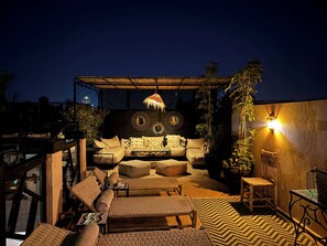 An outdoor seating area with a sofa, chairs, and a patterned rug. - Riad au Coeur de la Place Jamaa el Fna (Marrakesh)