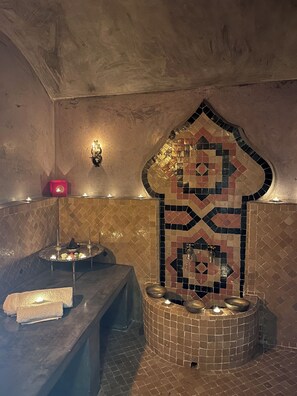 Ein Badezimmer mit Mosaikwand, einer Sitzbank und einer Wandleuchte.