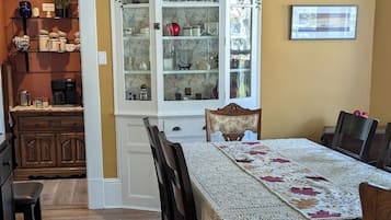 A dining area with a wooden table, chairs, a chandelier, and a cabinet with glass doors.