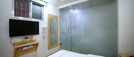 Una habitación de hotel con cama, televisión montada en la pared, armario y puerta corredera de cristal.