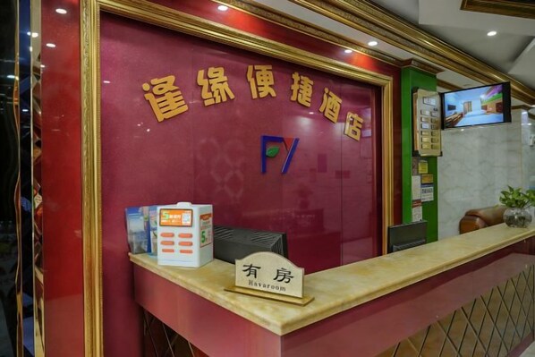 A reception desk with a sign indicating 'Hotel' and a television screen mounted on the wall. - Nanning Fengyuan Convenient Hotel No. 1 Affiliated Hospital of Medical University (Nanning)