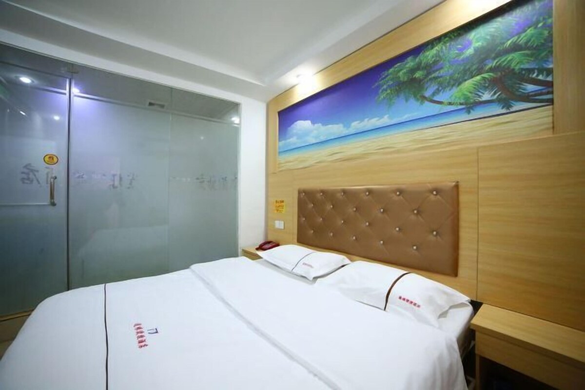 A hotel room with a bed, a glass door, and a mural of a beach scene.