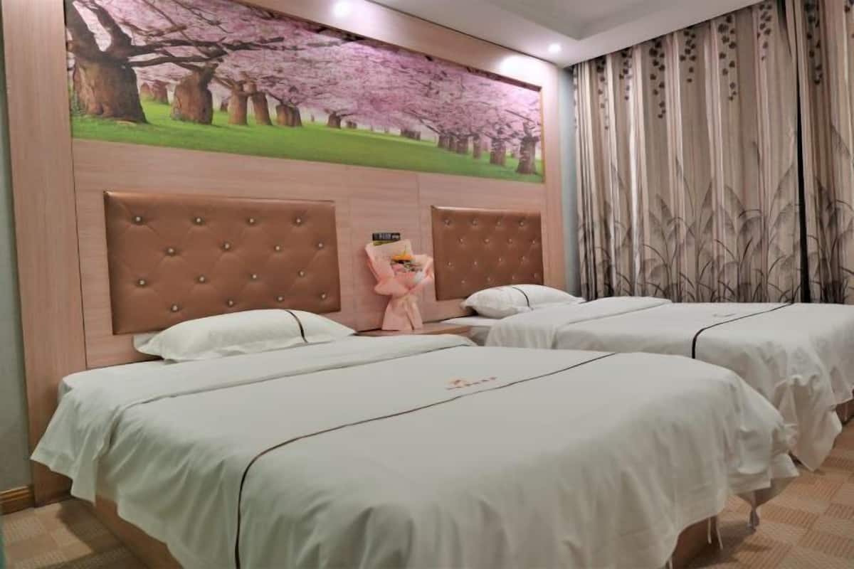 Quarto de hotel com duas camas, uma grande pintura de flores de cerejeira e cortina com padrão de folhas.