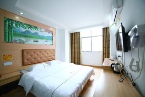 A hotel room with a bed, a painting of a landscape, a television, and a coffee maker. - Nanning Fengyuan Convenient Hotel No. 1 Affiliated Hospital of Medical University (Nanning)